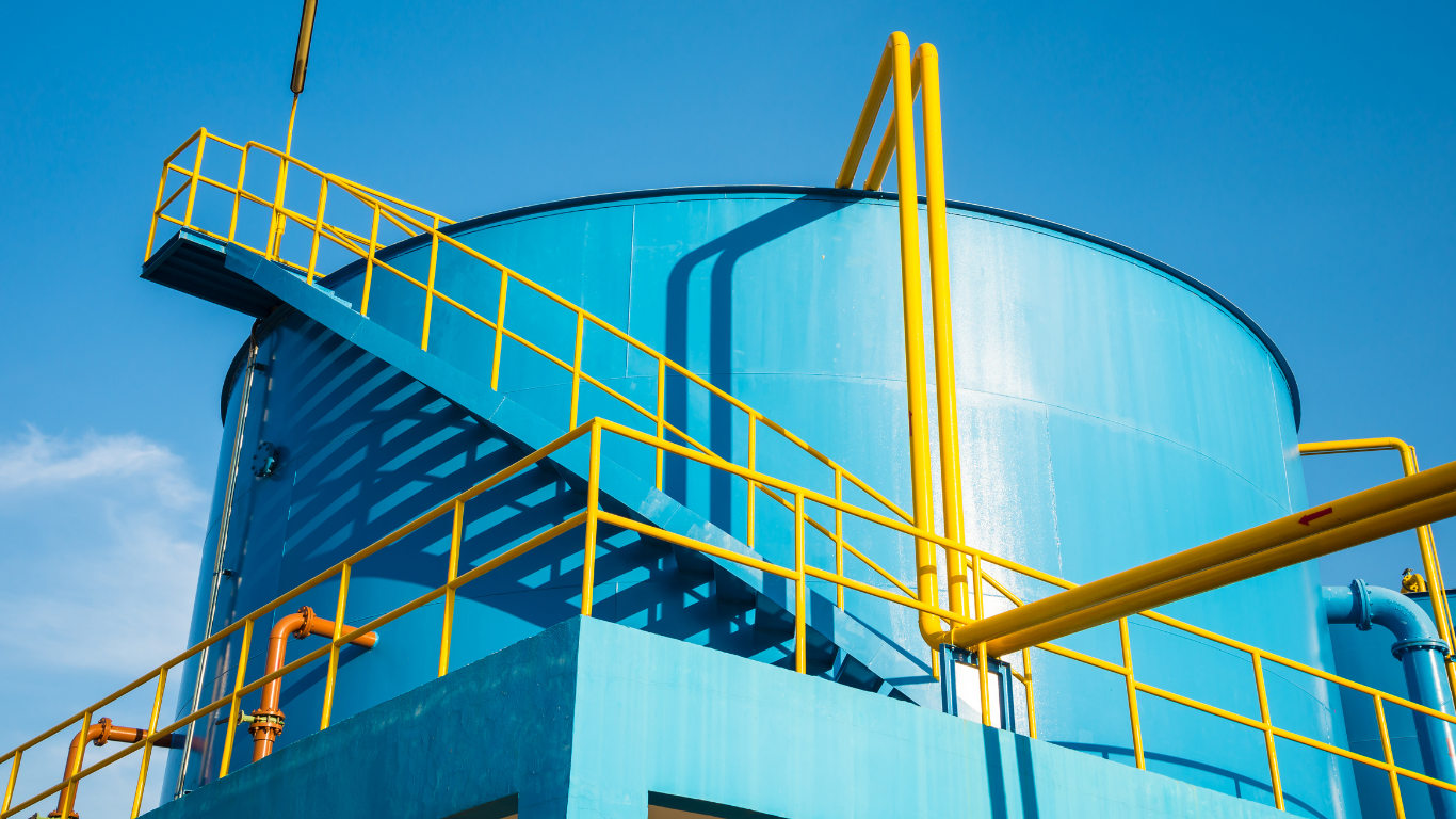 Industrial water recycling system featuring large blue tank and yellow pipes for wastewater treatment, rainwater reuse, and sustainable water management operations to improve water quality, reduce energy costs, and support environmental sustainability.